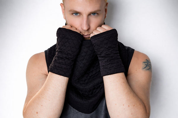 Black quilted fingerless gloves and scarf, close-up on texture, techwear accessories, minimal studio portrait, strong directional lighting