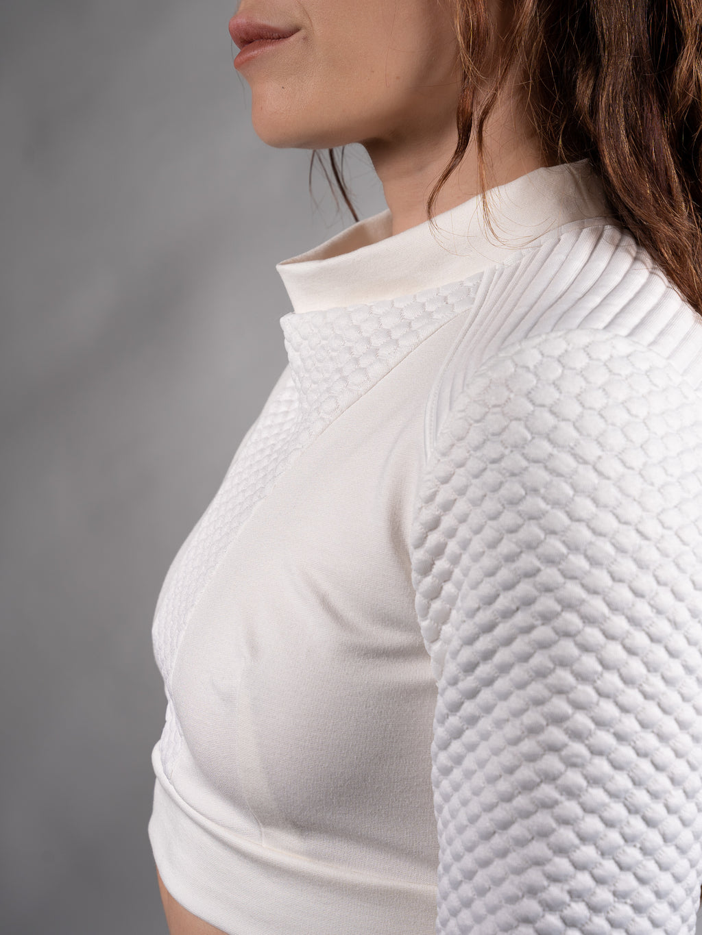 Close-up of sculptural draped collar folding into a soft pleat on white crop top – ZOLNAR