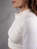 Close-up of sculptural draped collar folding into a soft pleat on white crop top – ZOLNAR