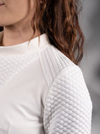 Close-up of ribbed shoulder panel and quilted sleeve on white crop top – ZOLNAR