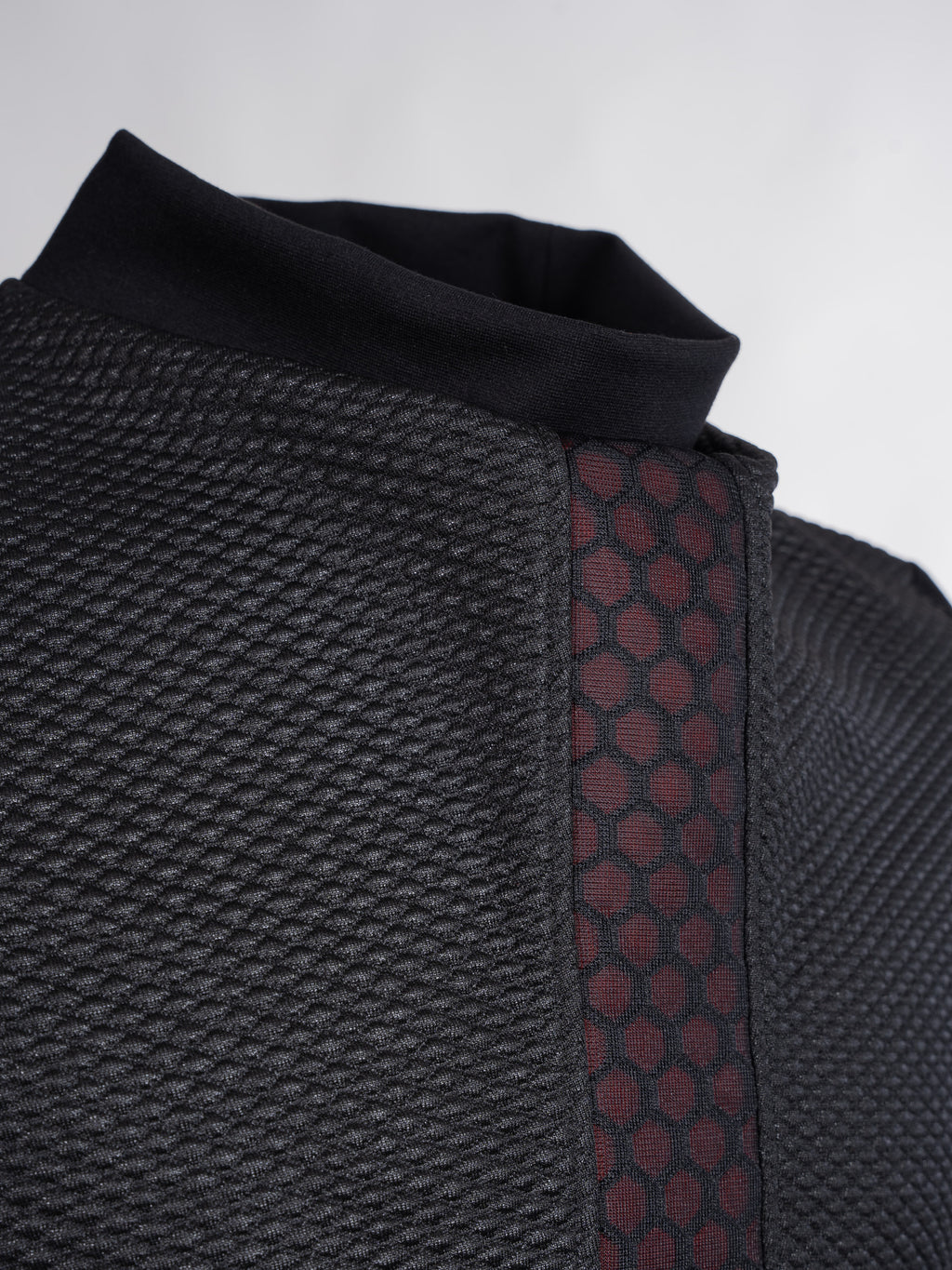 Close-up of a textured black garment with a patterned strap on a light gray background