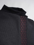 Close-up of a textured black garment with a patterned strap on a light gray background