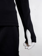 Person wearing a black long-sleeve top and pants on a white background