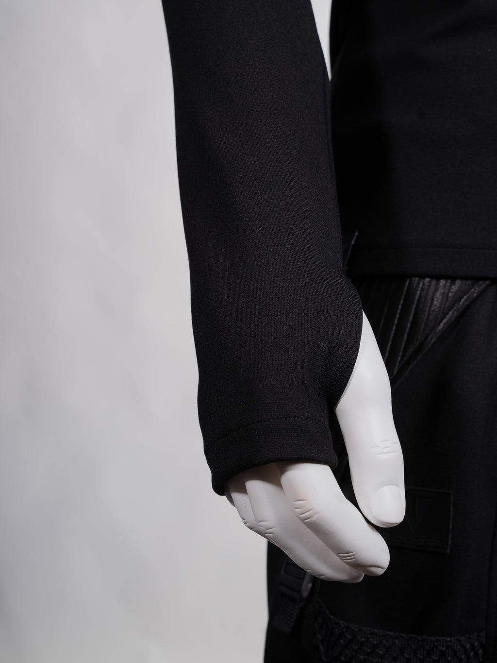Person wearing a black long-sleeve shirt and white gloves on a plain background