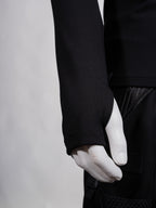 Person wearing a black long-sleeve shirt and white gloves on a plain background