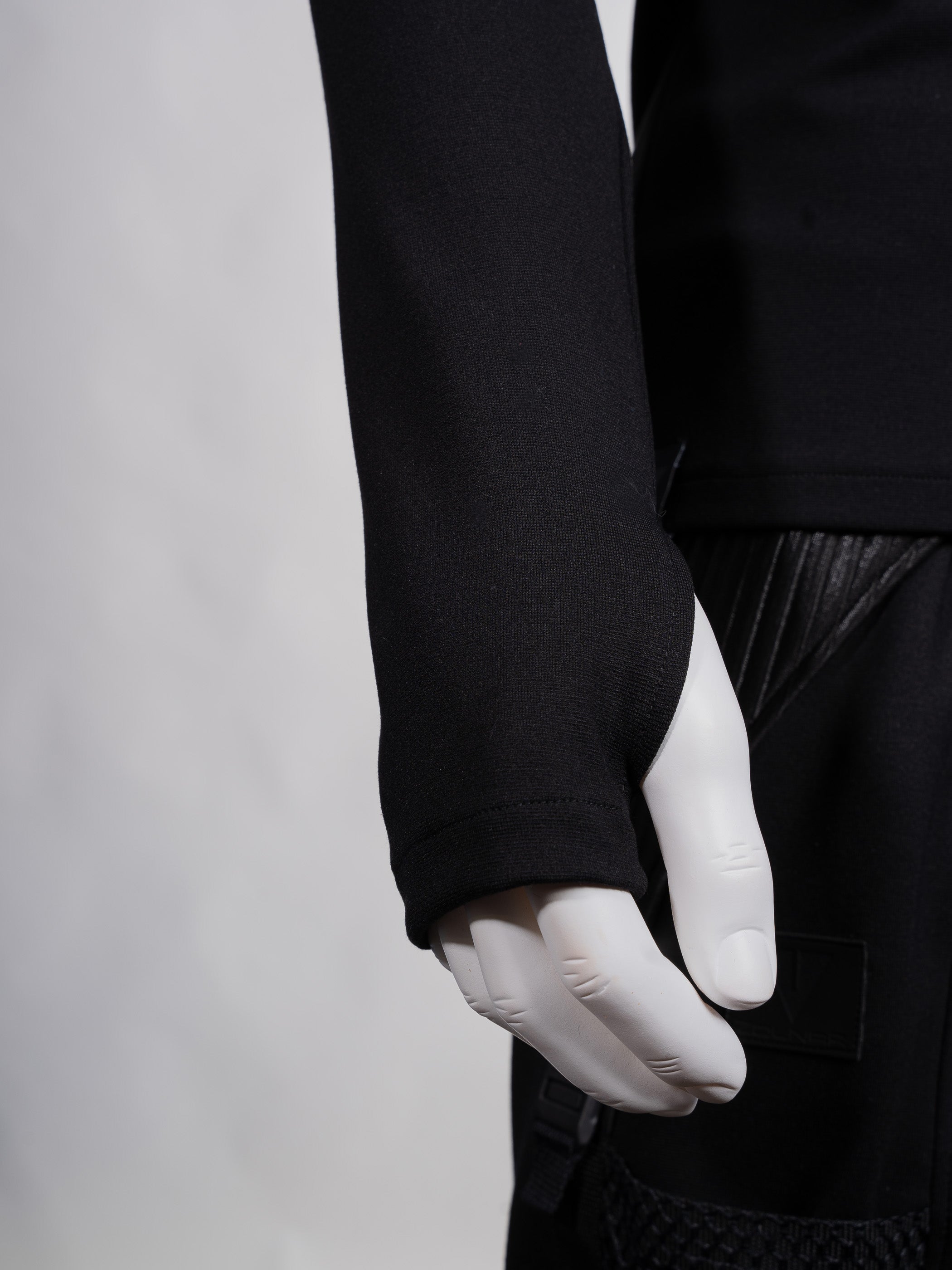 Person wearing a black long-sleeve shirt and white gloves on a plain background